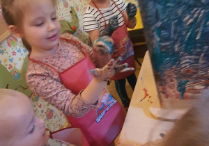 Marianka maluje za pomocą rączki.
